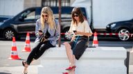 PARIS, FRANCE - JUNE 30: Veronika Heilbrunner is seen wearing grey jacket and Natasha Goldenberg is seen wearing black shorts, yellow stripped button shirt seen typing text message on their phone outside Acne during Paris Fashion Week - Haute Couture Fall/Winter 2019/2020 on June 30, 2019 in Paris, France. (Photo by Christian Vierig/Getty Images)

