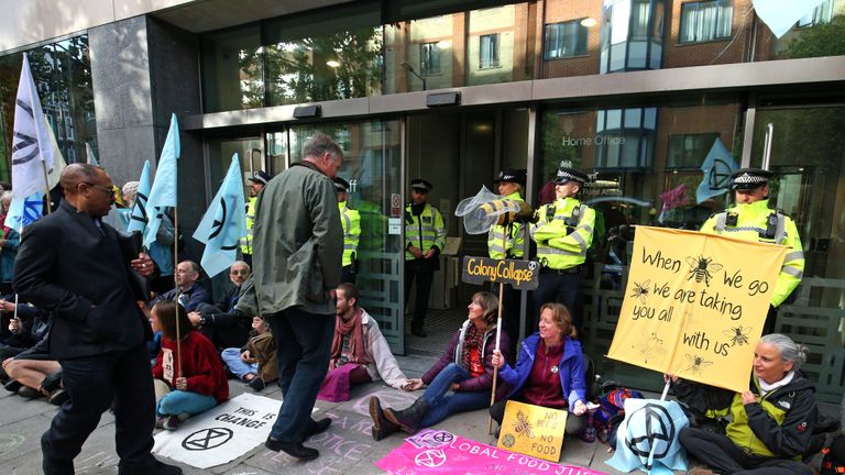 People enter the Department for Environment, Food and Rural Affairs, Marsham Street, passing police and protesters during an Extinction Rebellion (XR) protest in Westminster, London.