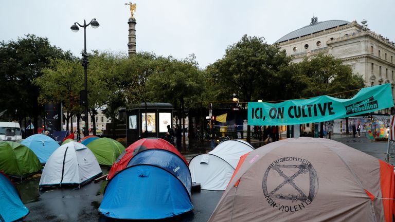 This picture taken on October 8, 2019, shows tents and a sign reading "Here we harvest" during a demonstration called by climate change activist group Extinction Rebellion, on the Pont au Change bridge in Paris. - Climate protesters from Sydney to London blocked roads starting on October 7, sparking mass arrests at the start of two weeks of civil disobedience demanding immediate action to save the Earth from "extinction". The year-old group Extinction Rebellion has energised a global movement demanding governments drastically cut the carbon emissions that scientists have shown to cause devastating climate change. (Photo by Thomas SAMSON / AFP) (Photo by THOMAS SAMSON/AFP via Getty Images)