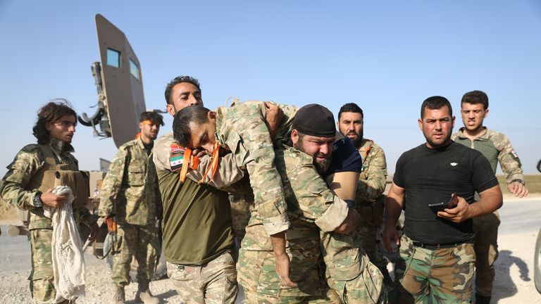 Turkish-backed Syrian fighters evacuate a wounded comrade near the border town of Ras al-Ain on October 13, 2019, as Turkey and it's allies continued their assault on Kurdish-held border towns in northeastern Syria. - Turkish forces and their proxies pushed deep into Syria Sunday, moving closer to completing their assault's initial phase, while Washington announced it was pulling out 1,000 troops from the country's north. (Photo by Nazeer Al-khatib / AFP) (Photo by NAZEER AL-KHATIB/AFP via Getty Images)