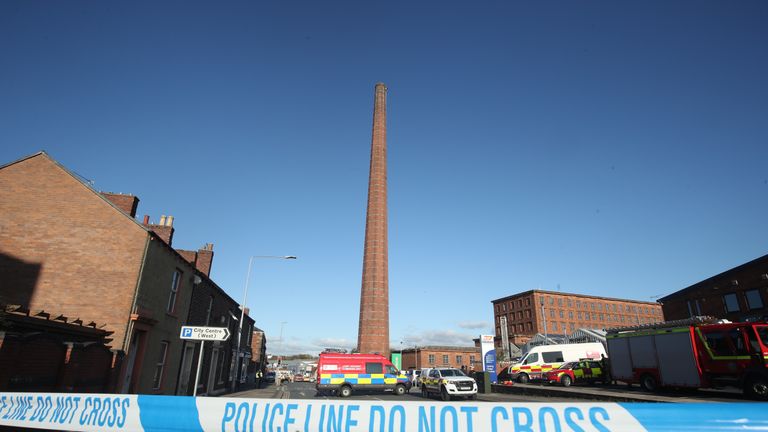 Emergency vehicles block the road near to Dixon's Chimney in Carlisle, Cumbria, where a man, whose condition is currently unknown, continues to hang upside down from the top of the chimney 270ft up.