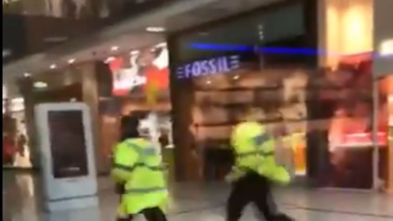 Police running through the Arndale Centre in Manchester. Pic: @GrizzleMarine /PA Wire