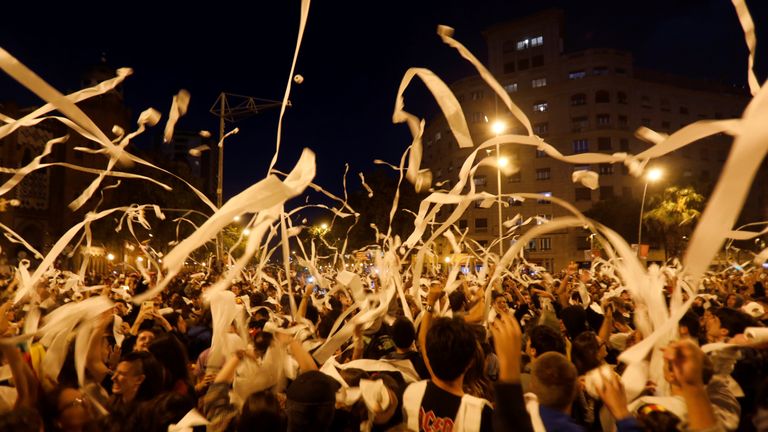 Protesters throw rolls of toilet paper into the air