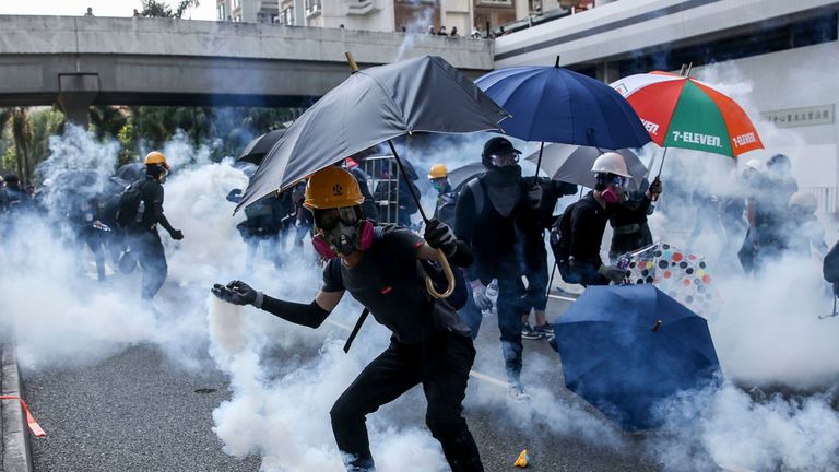 An anti-government protester tosses back a tear gas grenade during protests on National Day in Hong Kong, China