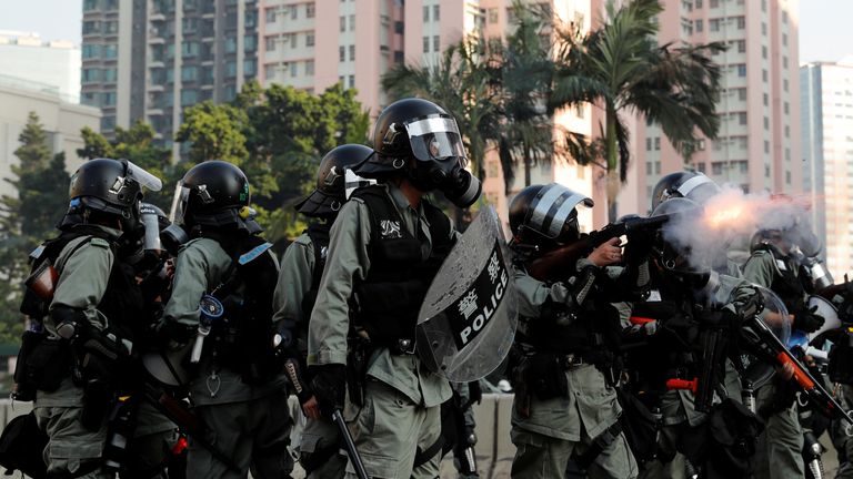 A riot police officer fires a tear gas canister 