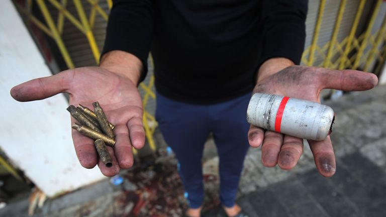 A protester holds the casings of live rounds (L) and a spent tear gas canister (R) reportedly fired by riot police