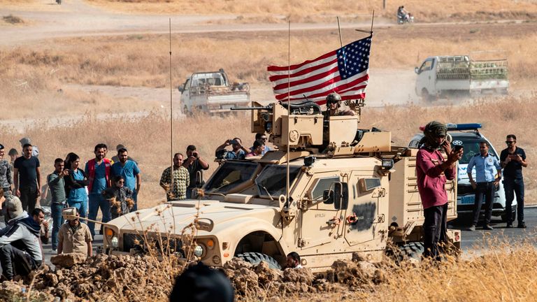 Syrian Kurds gather around a US armoured vehicle during a demonstration against Turkish threats to attack them