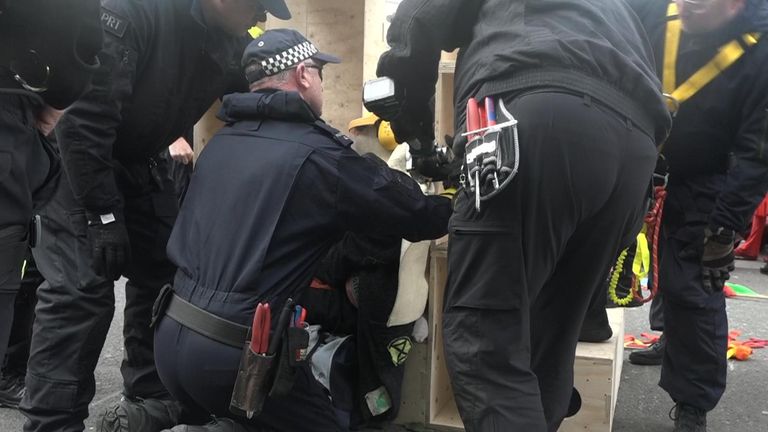 Specialist police officers free a protester who chained himself to a wooden structure