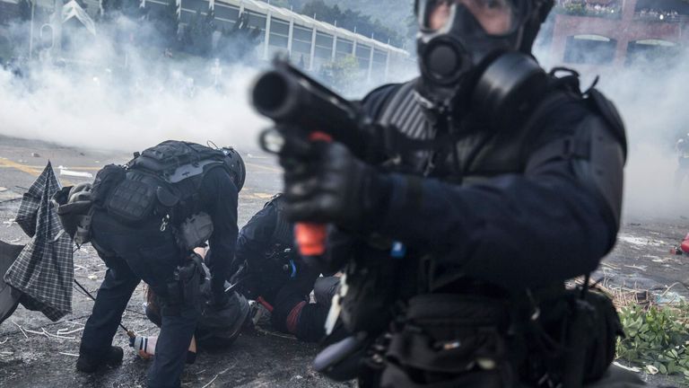 A riot police officer points his projectile launcher as his colleagues detain demonstrators in the Sha Tin district of Hong Kong on October 1, 2019