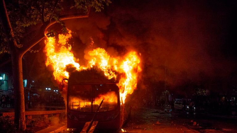 The bus was set alight after university students joined a mass fare-dodging protest in Santiago&#39;s metro