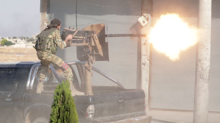 A Turkey-backed Syrian rebel fighter fires a weapon in the town of Tal Abyad