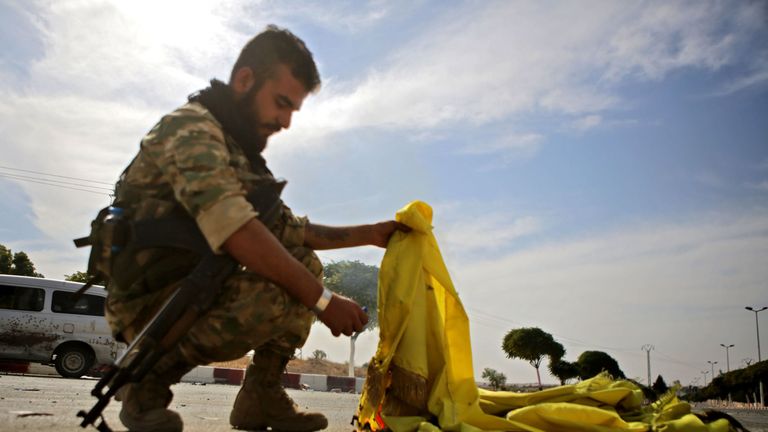 A Turkish-backed Syrian fighter burns the flag of the Syrian Democratic Forces (SDF) in the town of Ayn al-Arus, south of the border town of Tal Abyad, on October 14, 2019, as Turkey and its allies continue their assault on Kurdish-held border towns in northeastern Syria. - Syrian regime forces moved towards the Turkish border after Damascus reached a deal with beleaguered Kurdish forces following a US withdrawal announcement, AFP correspondents reported. (Photo by Bakr ALKASEM / AFP) (Photo by 