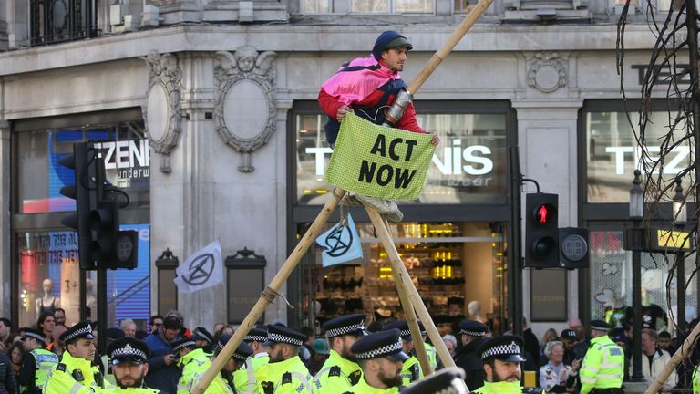 Police monitor as a climate activist perches on a make-shift structure in Oxford Street during the twelfth day of demonstrations by the climate change action group Extinction Rebellion