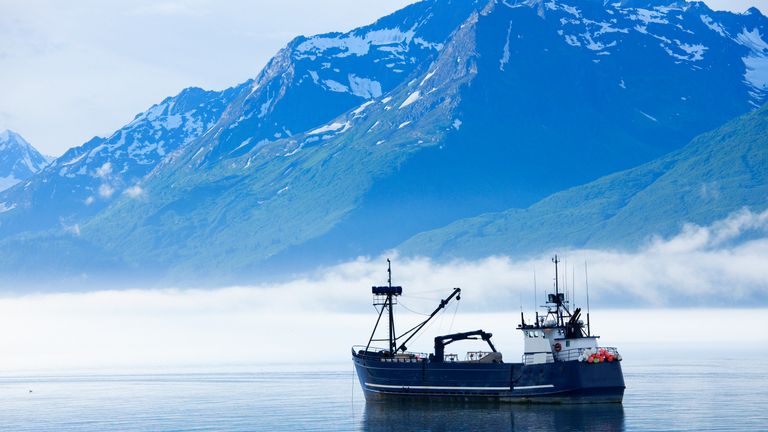 "Large fishing boat anchored in Valdez, Alaska bay. Chugach Mountains in background."