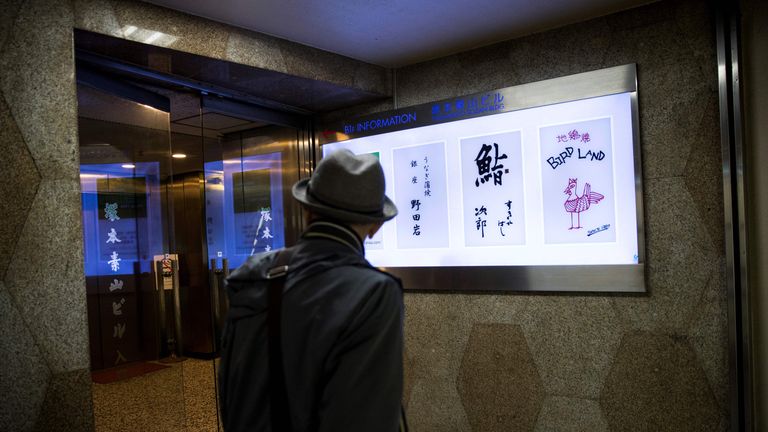 A man walks past the board of Sukiyabashi Jiro sushi restaurant (2nd R) in Tokyo on November 26, 2019. - The famed Tokyo sushi restaurant where Barack Obama is said to have enjoyed the best sushi of his life has been dropped from the latest Michelin gourmet guide after it stopped accepting reservations from the general public. (Photo by Behrouz MEHRI / AFP) (Photo by BEHROUZ MEHRI/AFP via Getty Images)