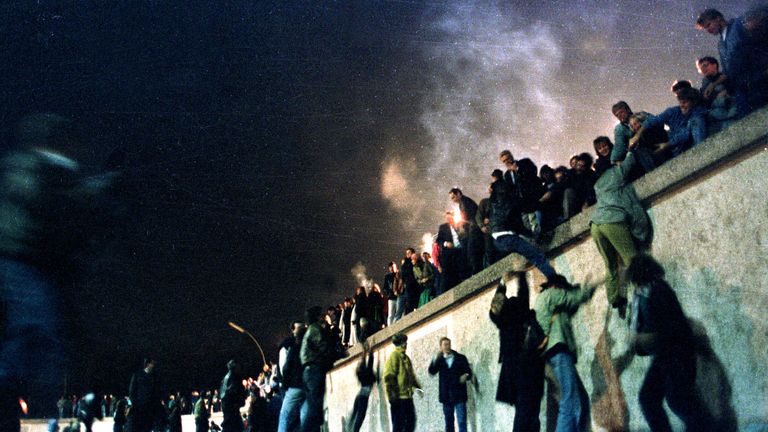 East German citizens climb the Berlin wall at the Brandenburg gate after the opening of the East German border was announced, November 10, 1989.
