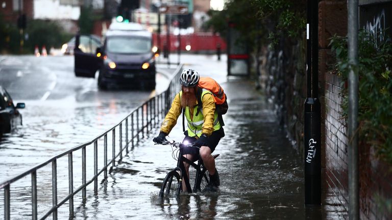 A man attempts to cycles through a flooded street in Sheffield