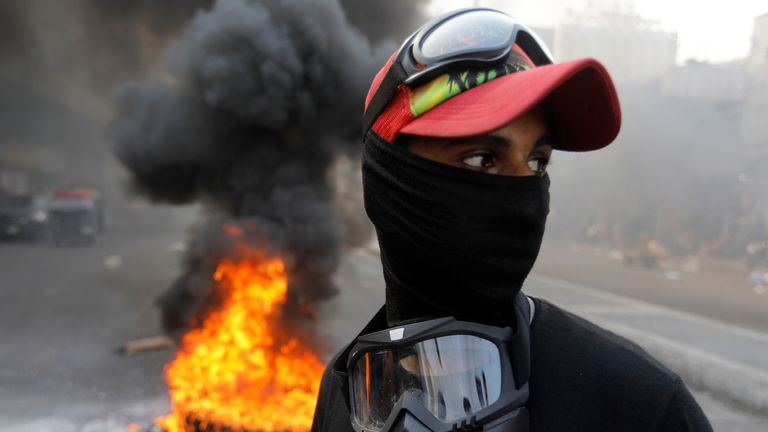 An Iraqi demonstrator is seen next to burning tires as he blocks the road in Baghdad