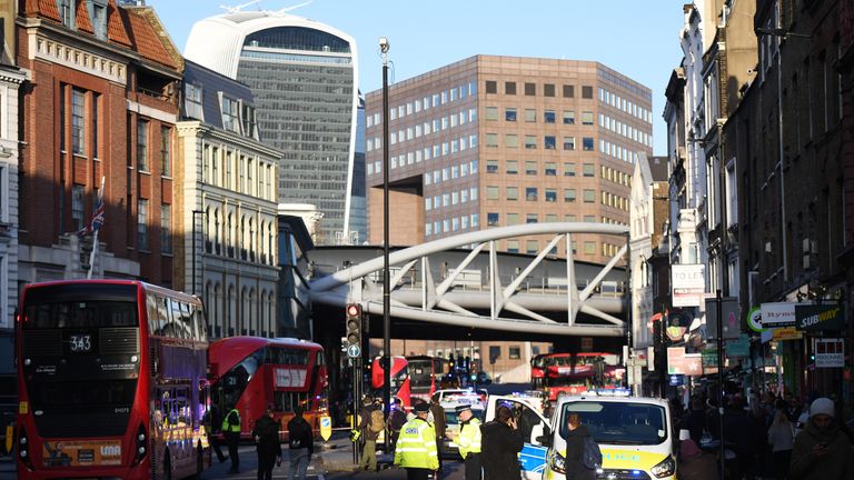 Traffic is stopped and members of the public are held behind a police cordon near Borough Market