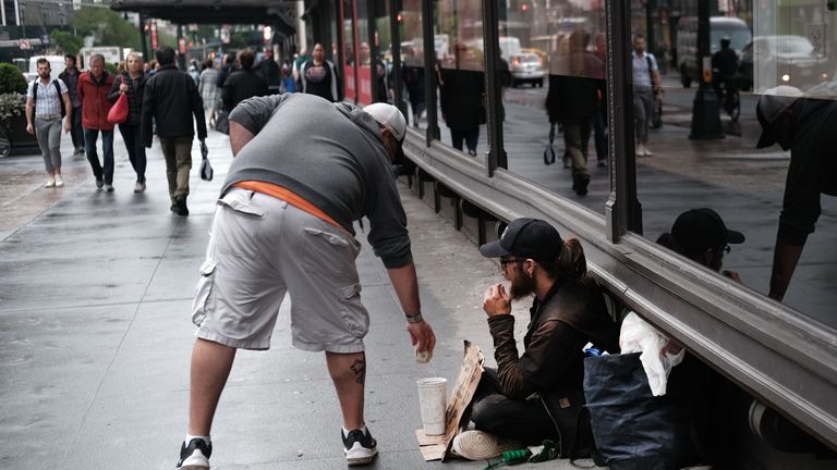 NEW YORK, NEW YORK - MAY 17: A man gives money to a person claiming to be homeless on a Manhattan sidewalk on May 17, 2019 in New York City. As New York City Mayor Bill de Blasio launches his bid for the presidency, some of New York’s most chronic social issues are getting renewed attention from critics of the mayor who say he hasn’t done enough for the city to justify a presidential run. Homelessness, an issue that has persisted in New York for generations, hit a record-breaking peak in January with nearly 64,000 men, women, and children sleeping in shelters each night. According to a report by the Coalition for the Homeless, that figure is expected to increase by 5,000 in 2022. (Photo by Spencer Platt/Getty Images)