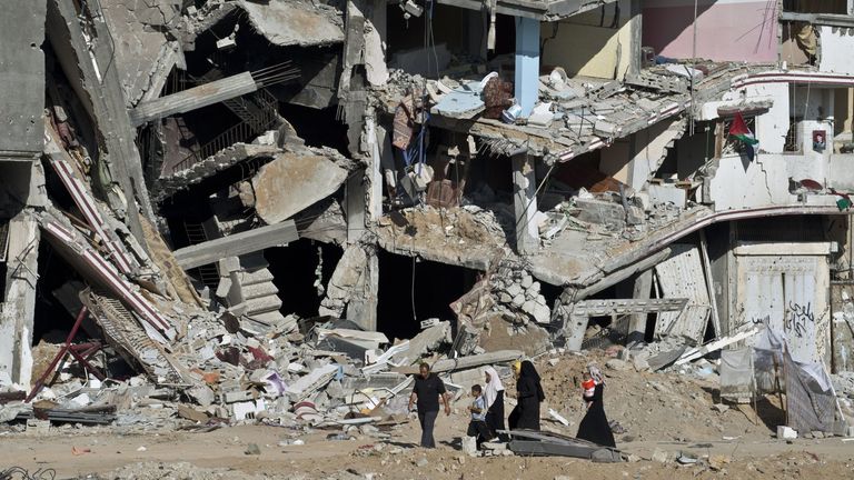 A family in Gaza walks past the remains of a building destroyed in fighting between Hamas and Israel