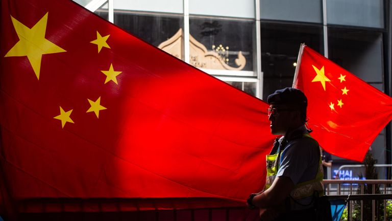 A police officer stands guard in front of Chinese flags as pro-Beijing demonstrators hold a counter-rally during a protest march in Hong Kong on July 1, 2018, to coincide with the 21st anniversary of the city&#39;s handover from British to Chinese rule. (Photo by Philip FONG / AFP) (Photo credit should read PHILIP FONG/AFP via Getty Images)
