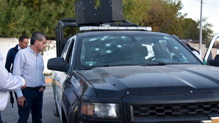 Coahuila state Governor Miguel Riquelme Solis looks at a police vehicle shot during a gunbattle