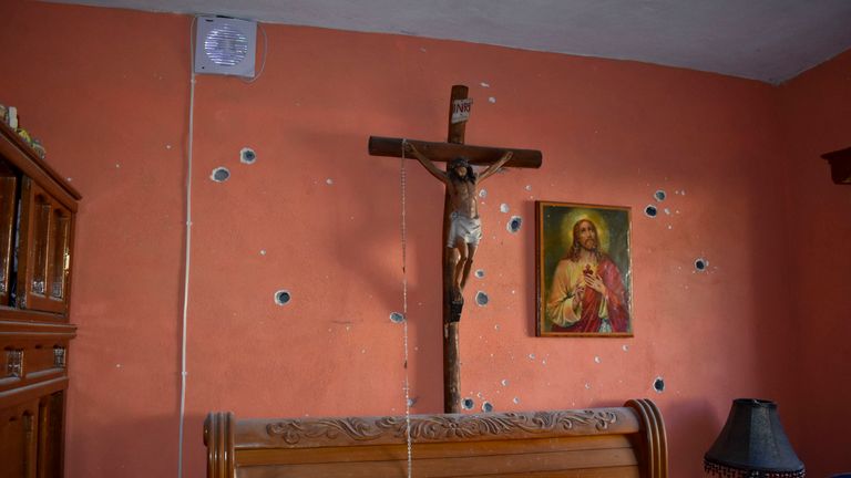 A wall of the room of a home is riddled with bullet holes