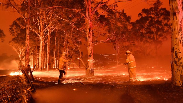 This timed-exposure image shows firefighters hosing down trees as they battle against bushfires around the town of Nowra in the Australian state of New South Wales on December 31, 2019