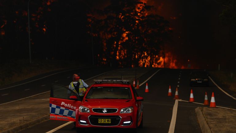 A New South Wales Police officer prepares to flee his roadblock on the Princes Highway near the town of Sussex Inlet on December 31, 2019 in Sydney, Australia