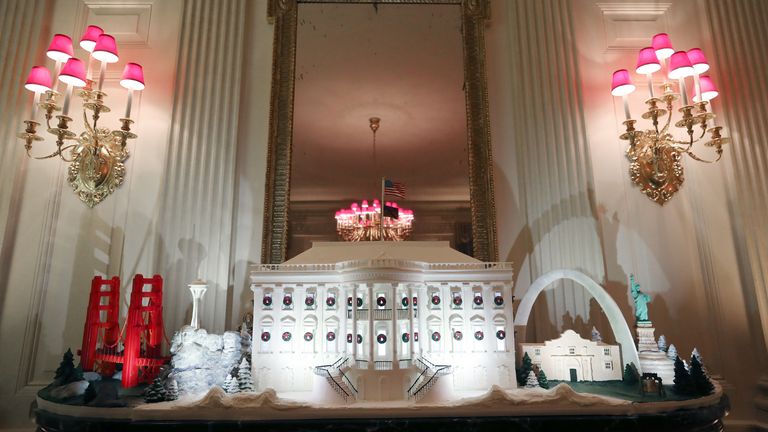 A miniature Golden Gate Bridge and St Louis Gateway Arch stand next to a gingerbread White House in the State Dining Room 