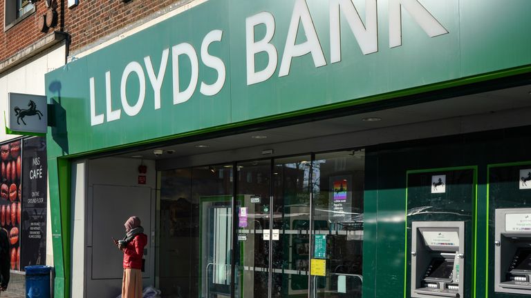 London, United Kingdom - February 03, 2019: Unknown woman checking her mobile in front of Lloyds Bank branch at Lewisham on sunny morning. It is one of "Big Four" clearing banks in UK.