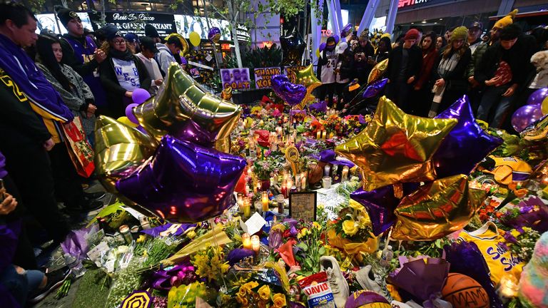 People gather in front of a makeshift memorial for former NBA and Los Angeles Lakers player Kobe Bryant and his daughter Gianna Bryant, who were killed with seven others in a helicopter crash on January 26, at LA Live plaza in front of Staples Center in Los Angeles on January 27, 2020. - Federal investigators sifted through the wreckage of the helicopter crash that killed basketball legend Kobe Bryant and eight other people, hoping to find clues to what caused the accident that stunned the world. (Photo by FREDERIC J. BROWN / AFP) (Photo by FREDERIC J. BROWN/AFP via Getty Images)