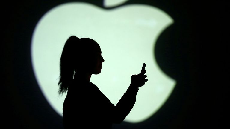 Silhouette of mobile user is seen next to a screen projection of Apple logo in this picture illustration taken March 28, 2018. 
