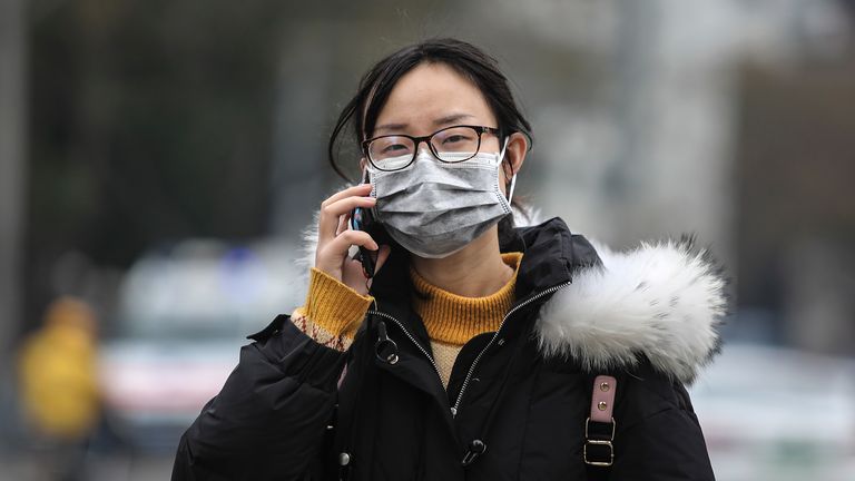 A woman wears a mask near the Huanan seafood market where the virus is thought to have originated