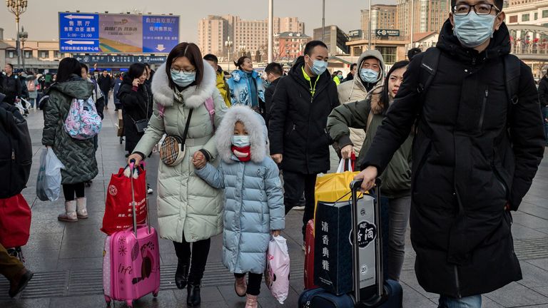 People wearing protective masks arrive at Beijing railway station to head home for the Lunar New Year on January 21, 2020