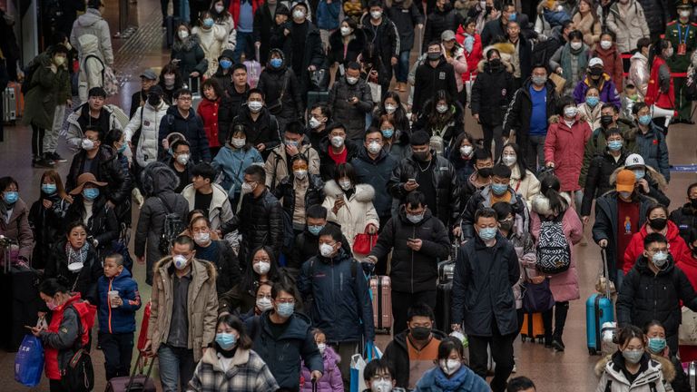 Chinese passengers, most wearing masks, arrive to board trains before the annual Spring Festival at a Beijing railway station 