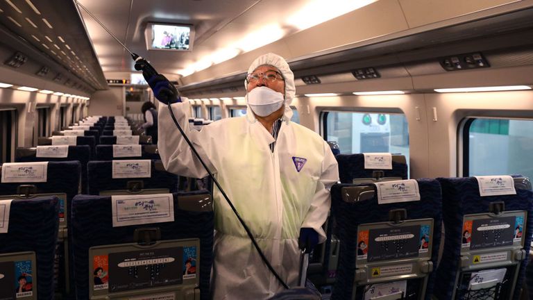 A disinfection worker wearing protective gears spray anti-septic solution on a train in Seoul, South Korea