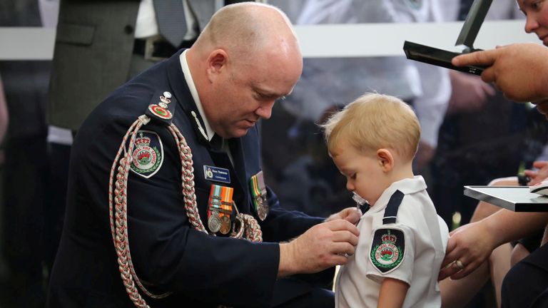 RFS Commissioner Shane Fitzsimmons presents a posthumous Commendation for Bravery and Service to the son of RFS volunteer Geoffrey Keaton. Pic: NSW Rural Fire Service/Reuters