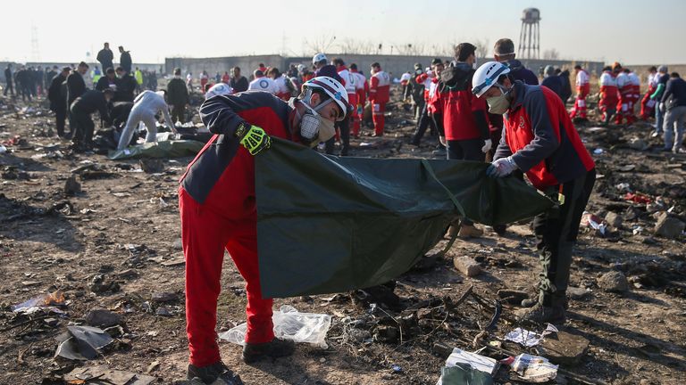 Red Crescent workers check plastic bags at the site where the Ukraine International Airlines plane crashed