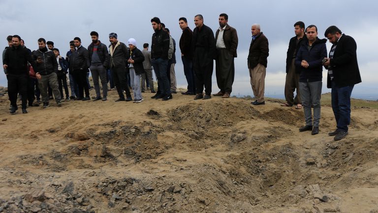 Men look over a crater caused by a missile fired by Iran at US-led coalition forces in Duhok, Iraq 