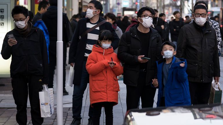 Chinese tourists wearing masks walk through the Ginza shopping district in Tokyo, Japan