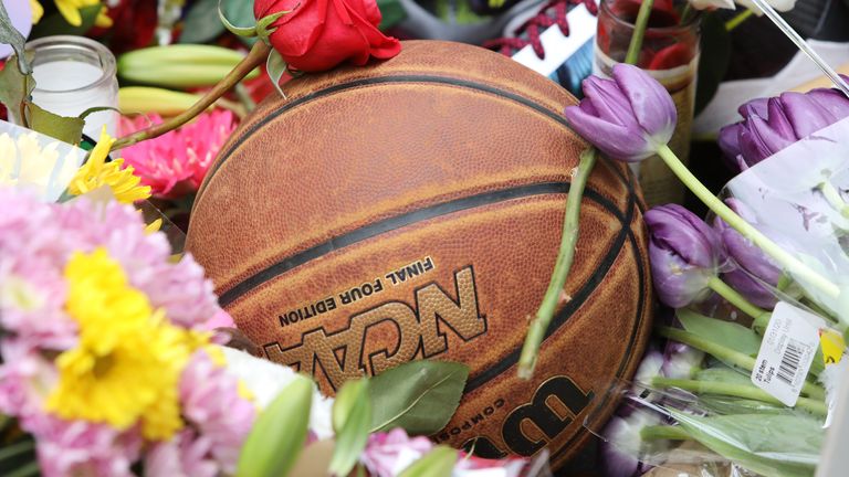 A basketball lies amid flowers at a makeshift shrine at the Staples Center in LA/