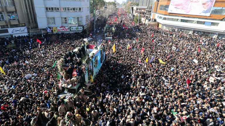 Iranian mourners gather around a vehicle carrying the coffin of Qassem Soleimani 