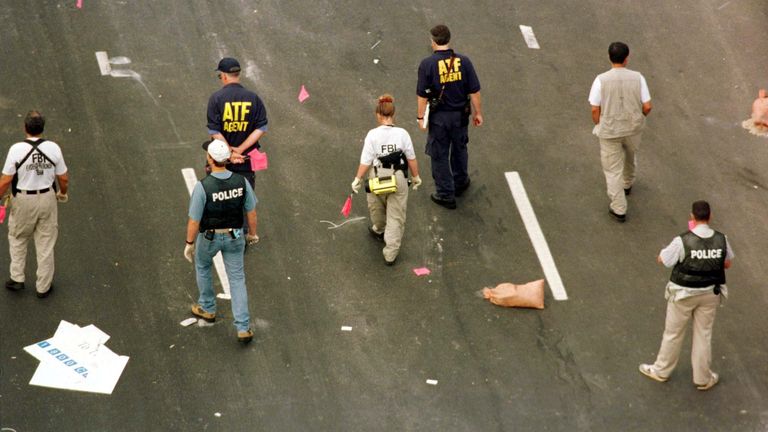 Alcohol, Tobacco and Firearms agents, FBI agents and local police officers carry red flags to mark evidence in their investigation of a suspected pipe bomb blast which exploded in Centennial Olympic Park in Atlanta, early July 27 1996