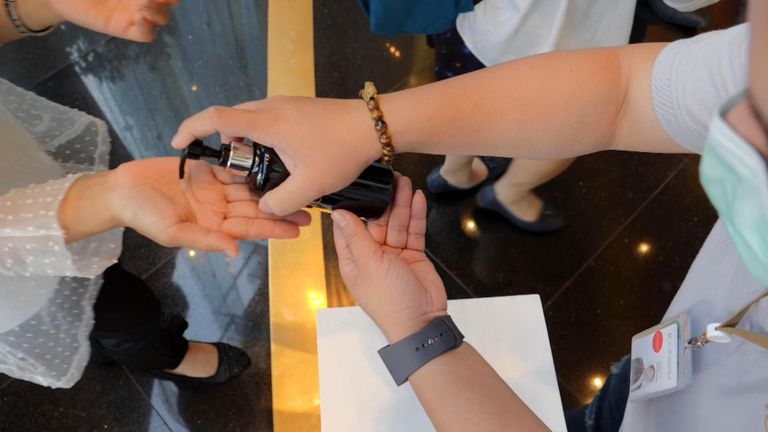 Disinfectant is pumped into people's hands as they go shopping