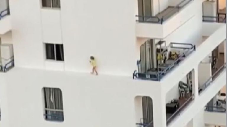 The toddler is seen scurrying across the narrow edge of a block of flats in Tenerife