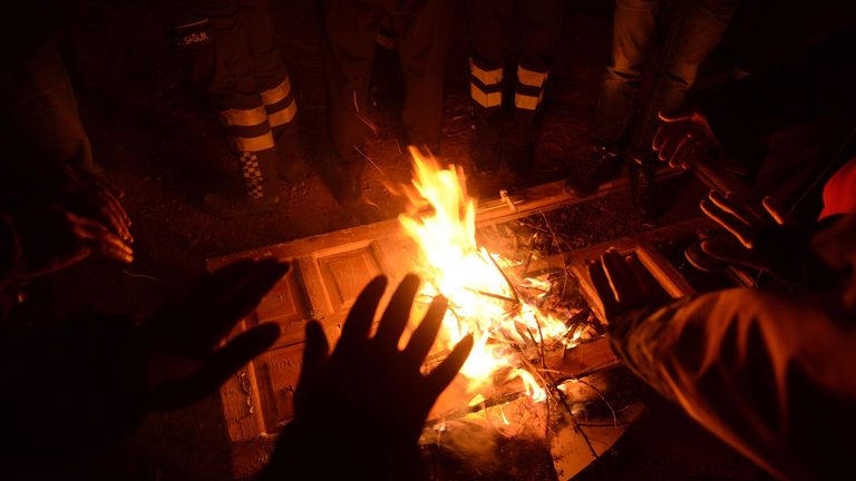 Turkish officials and police try to keep warm at the scene of a collapsed building