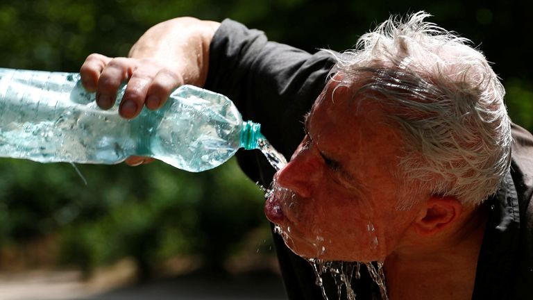 A man cools off with a bottle of water on a hot summer day in a park in Brussels, Belgium