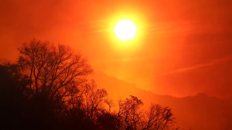 The sun rises over a smoldering landscape that was burned by a wildfire dubbed the Cave Fire, burning in the hills of Santa Barbara, California, US